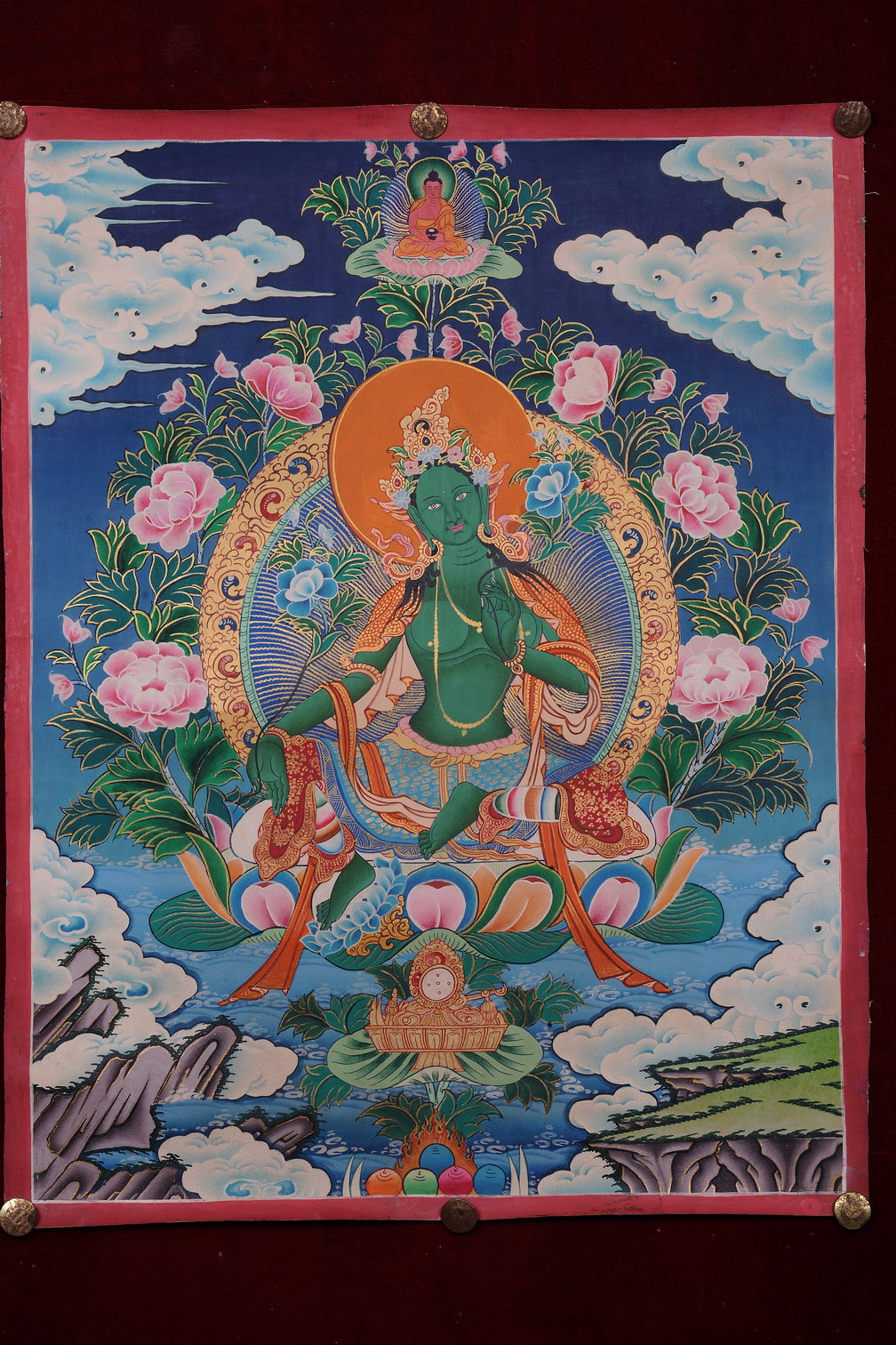 Green Tara thangka painting showing the green deity seated on a lotus with a gold halo and flowers