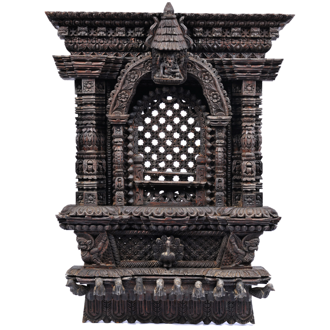 Dark, densely carved wooden Kumari window with a lattice centre and a small Ganesh figure at the crown