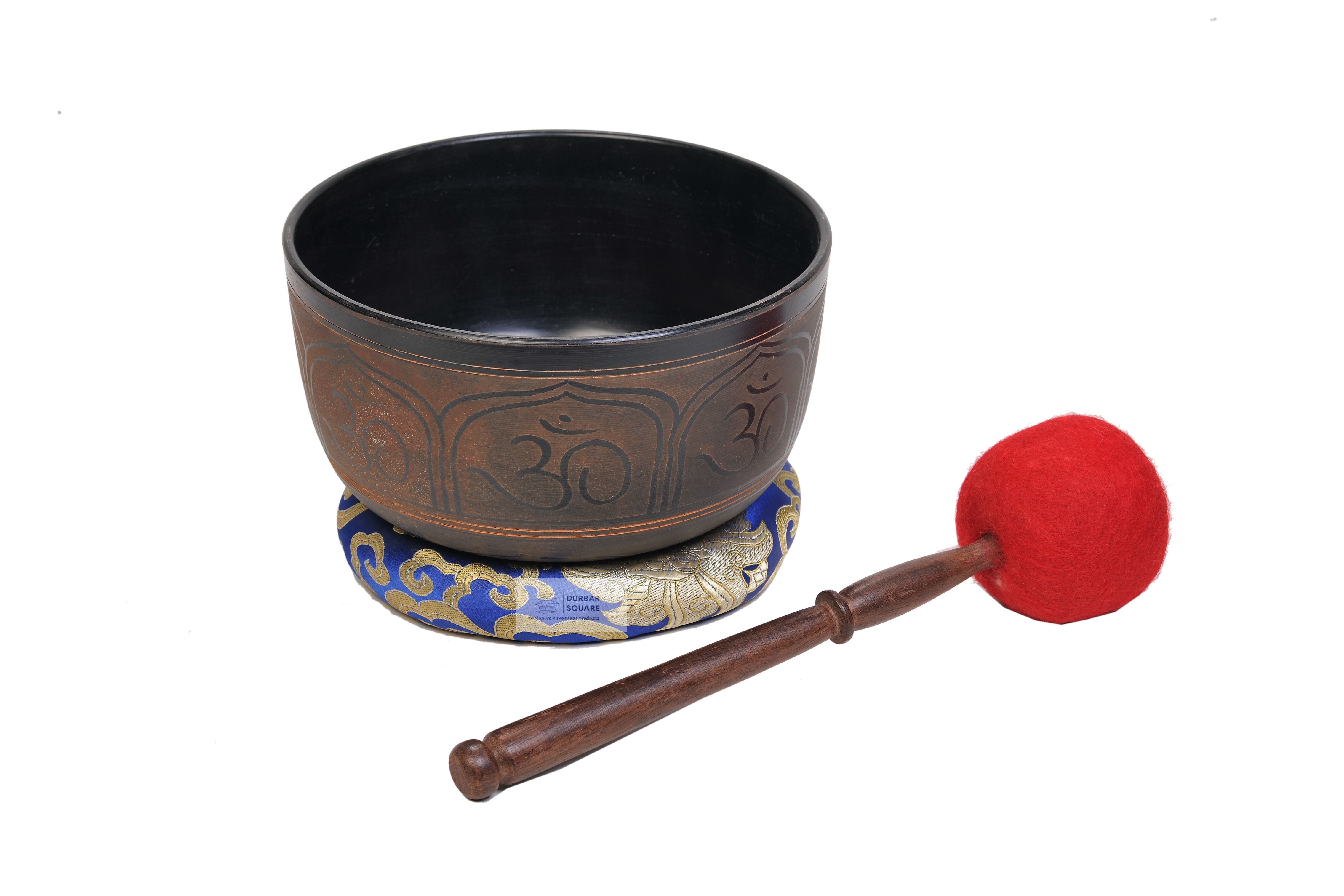 Dark singing bowl etched with Om symbols in panels around the body, with cushion and mallet
