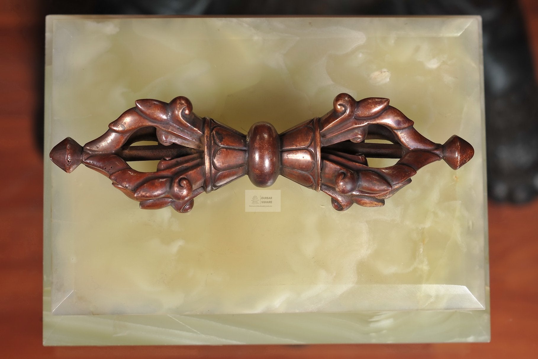 Handcrafted copper vajra with five prongs at each end on a marble plate