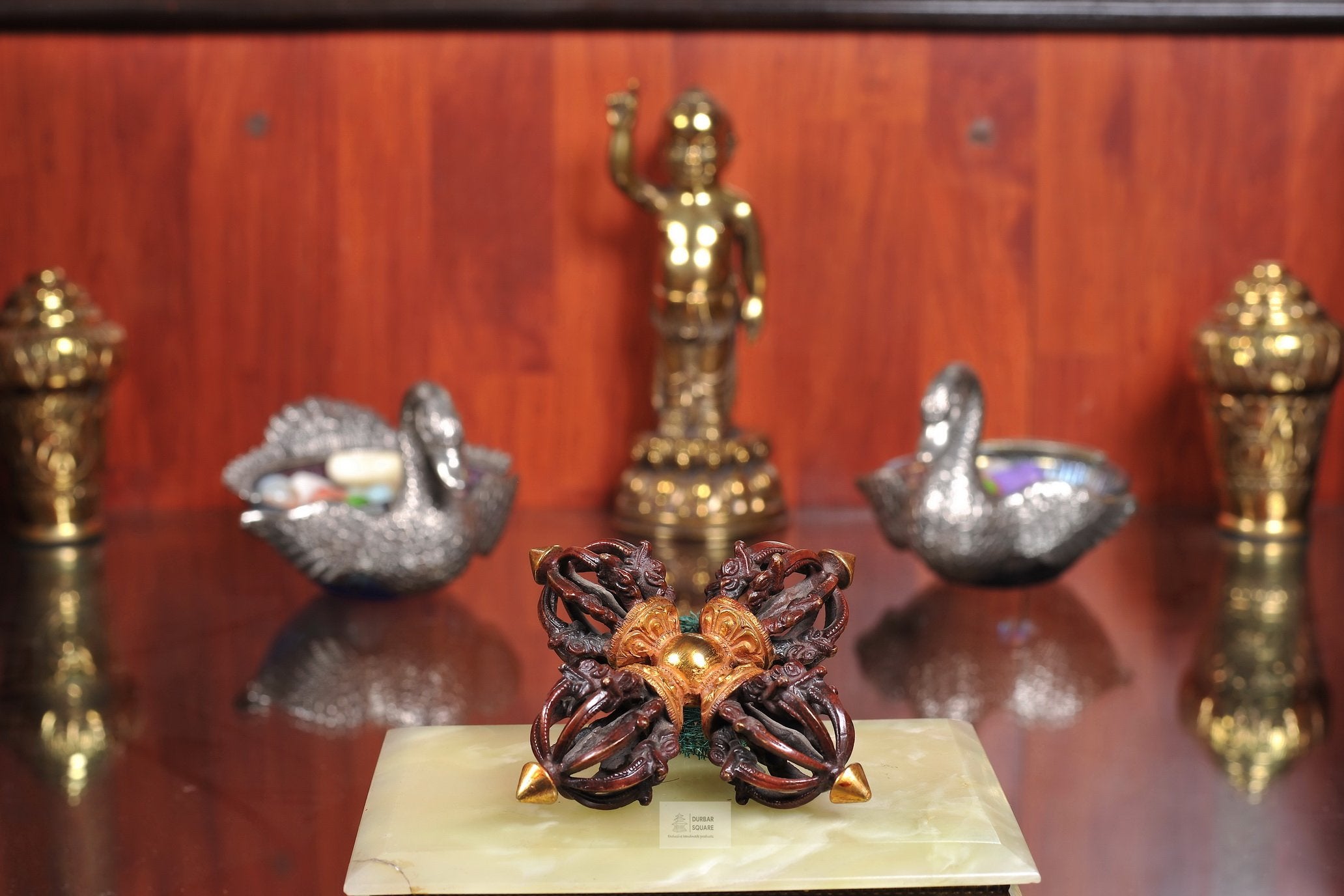 Gold-plated copper double vajra (Bishwa Bajra) with four heads around a central hub, displayed on a home shrine