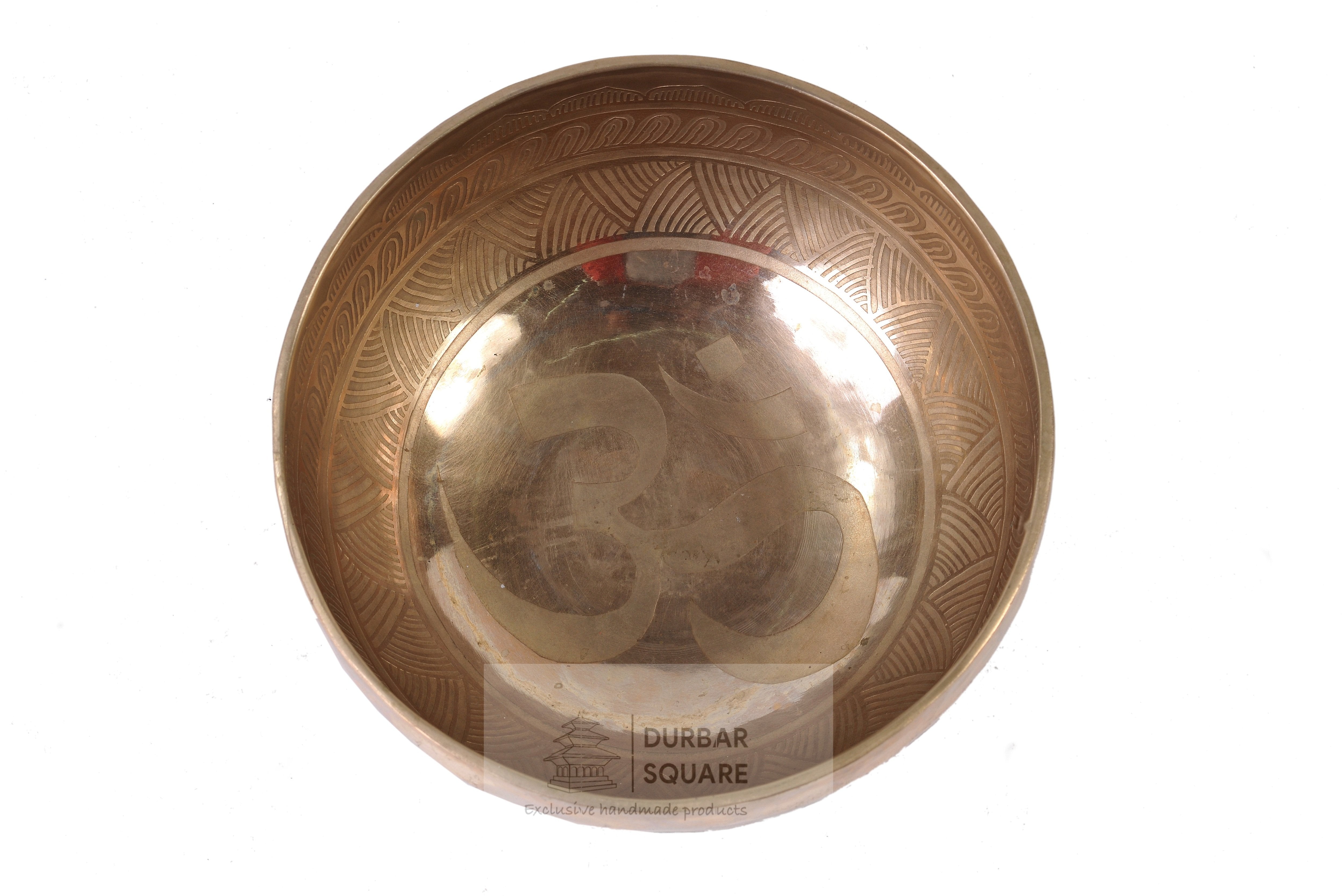 Brass singing bowl with an etched Om symbol inside and a patterned rim